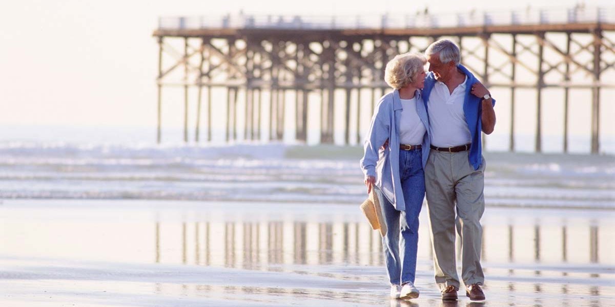 retired couple walking along beach